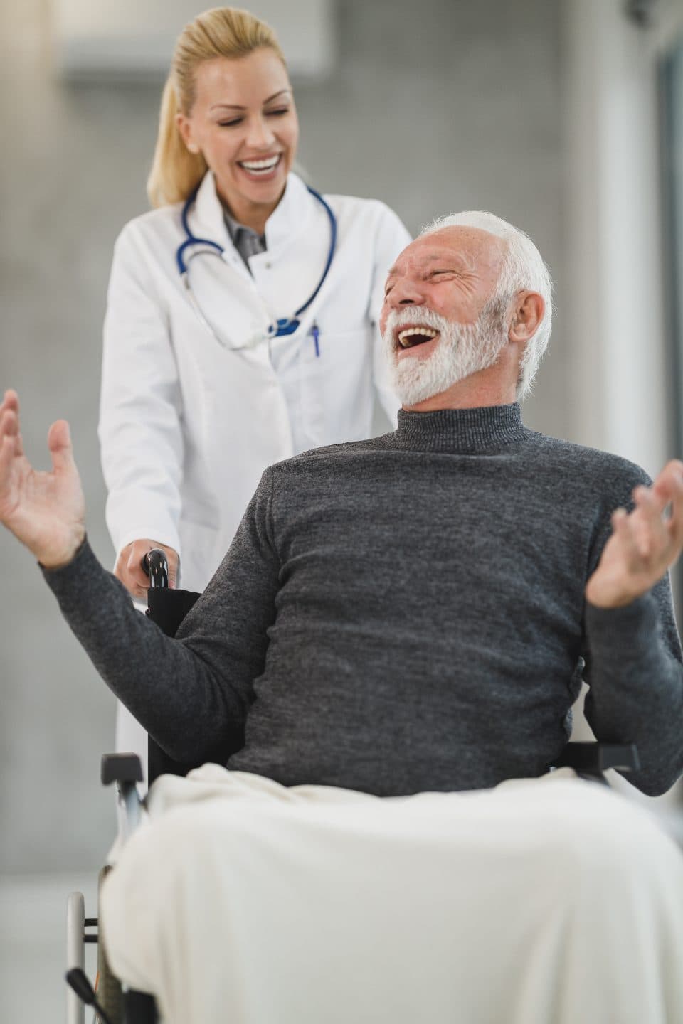 An older man laughing with a care worker beside him