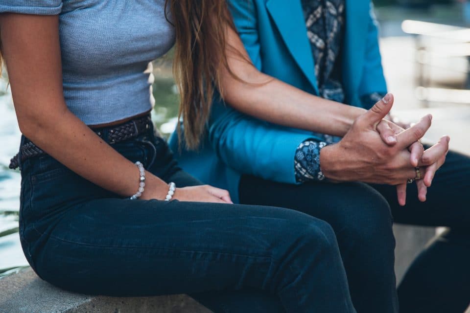 A younger person holding an older person's hands, offering comfort